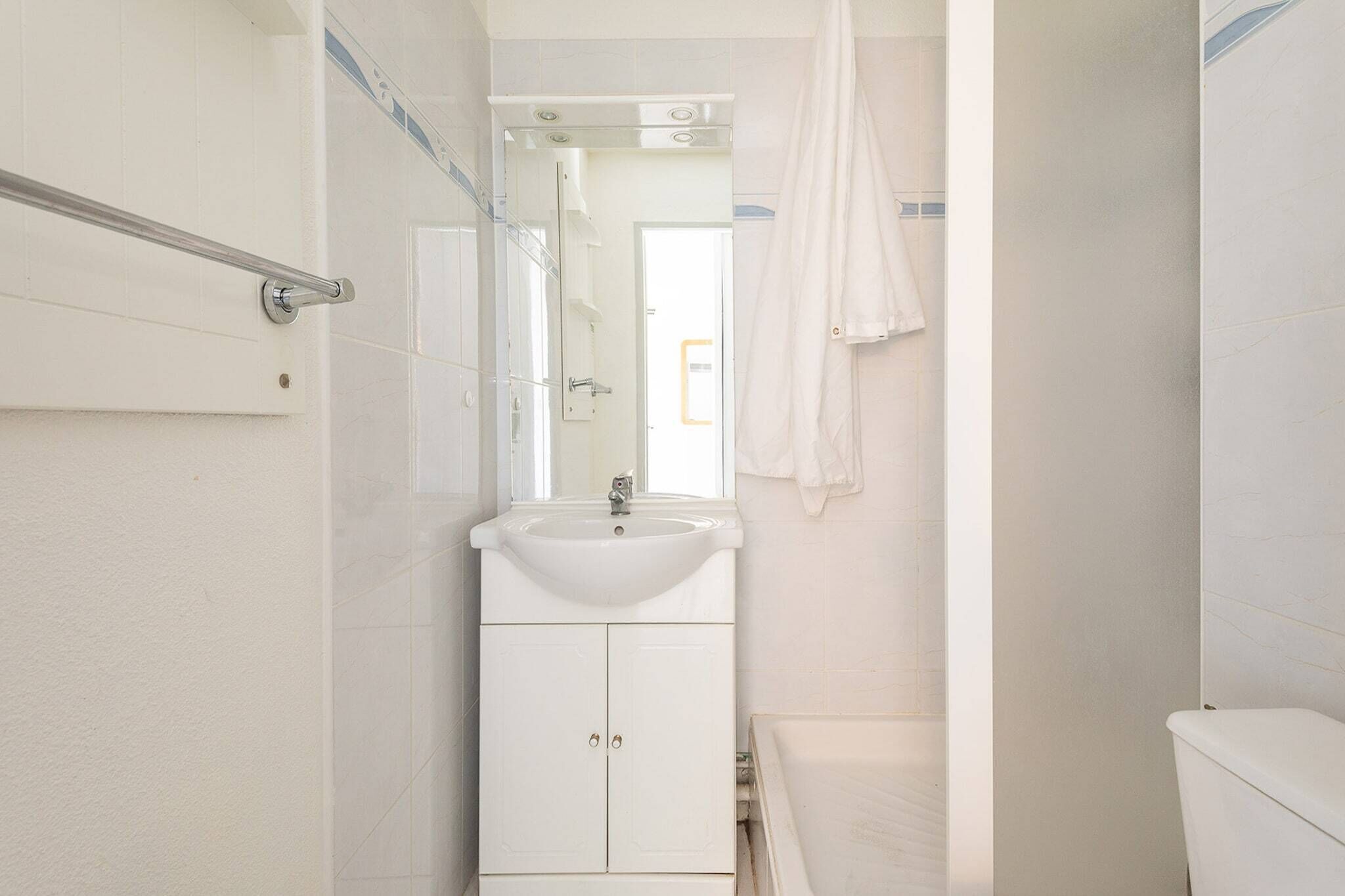 A bathroom with a white sink, mirror, and shower.