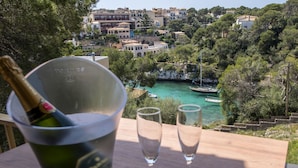 Une table avec une bouteille de champagne et deux verres, donnant sur une ville côtière avec ses bâtiments et ses bateaux.