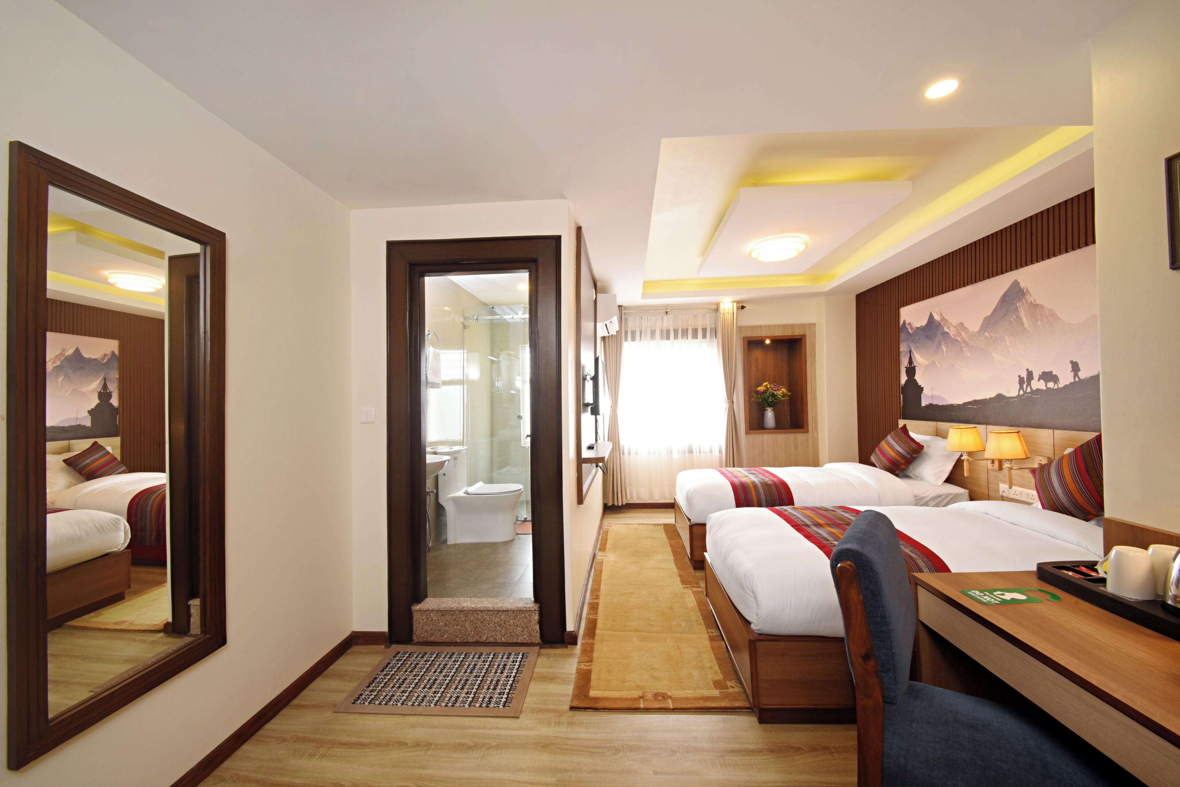 A hotel room with a bed, a desk, a mirror, and a bathroom visible through an open door.