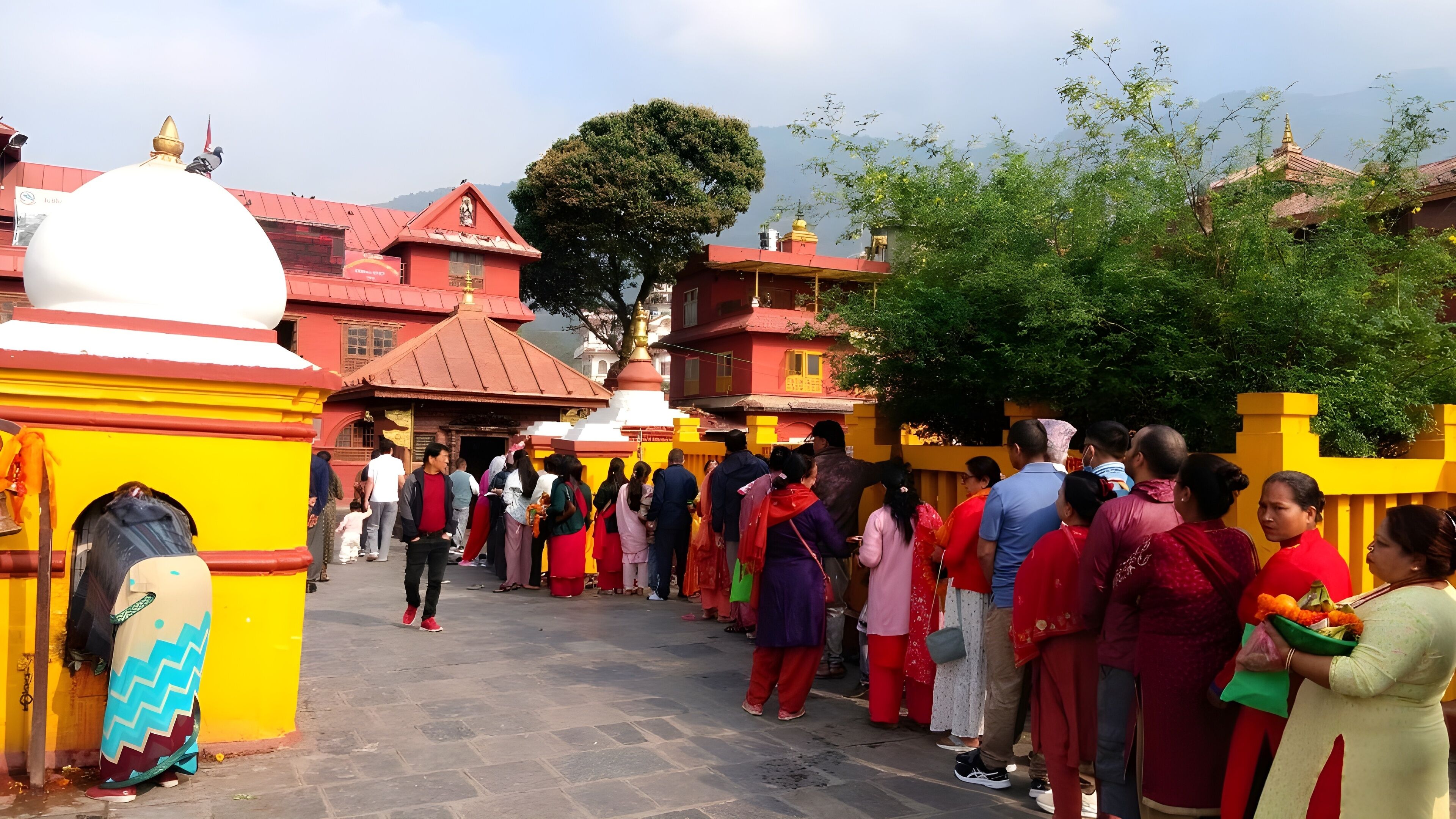 Un grupo de personas reunidas frente a la entrada de un templo con arquitectura tradicional y un cielo despejado al fondo.