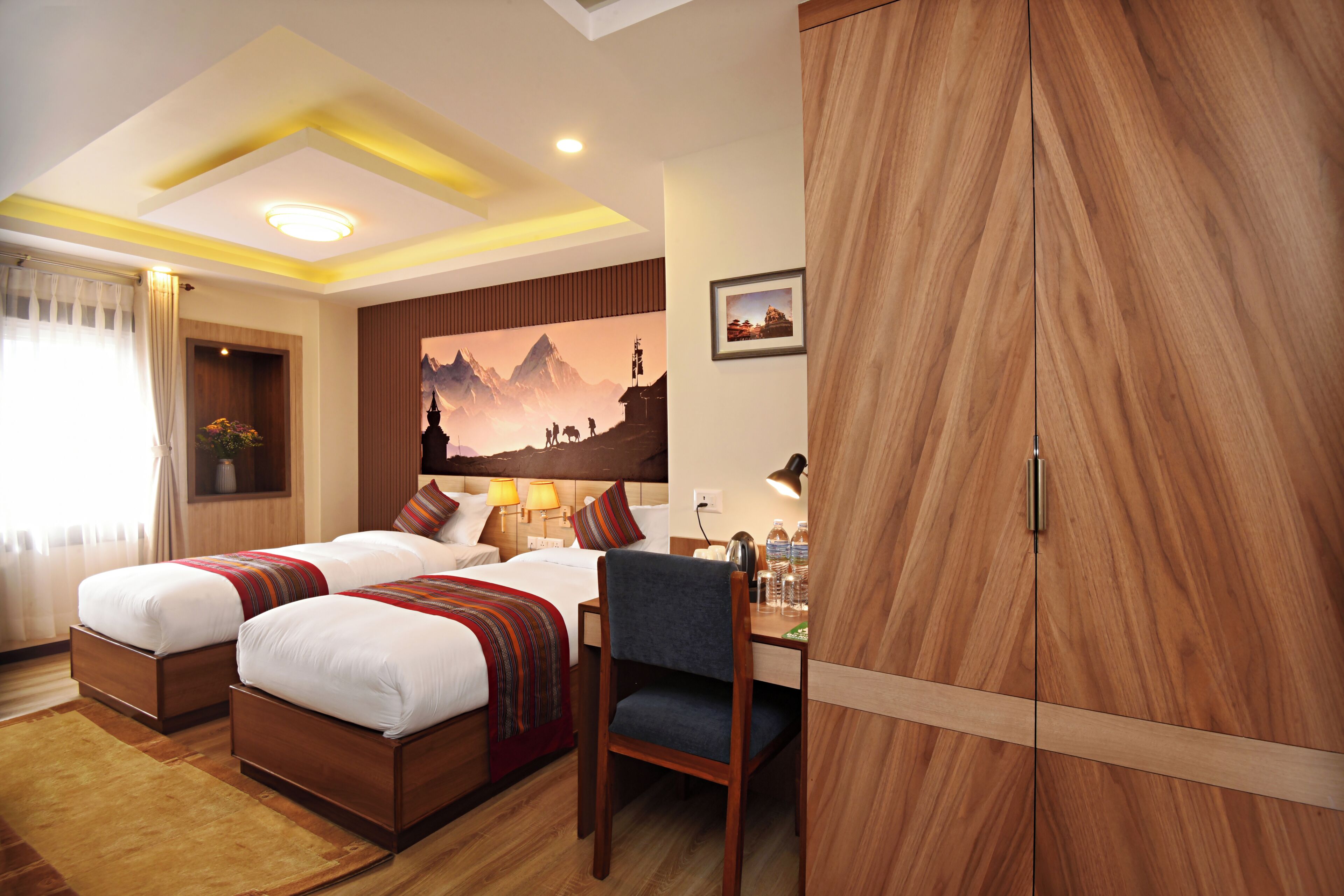 A hotel room with two beds, a desk, and a wardrobe.