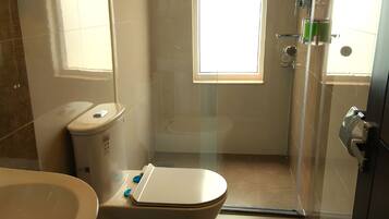 A bathroom with a toilet, sink, and shower area.