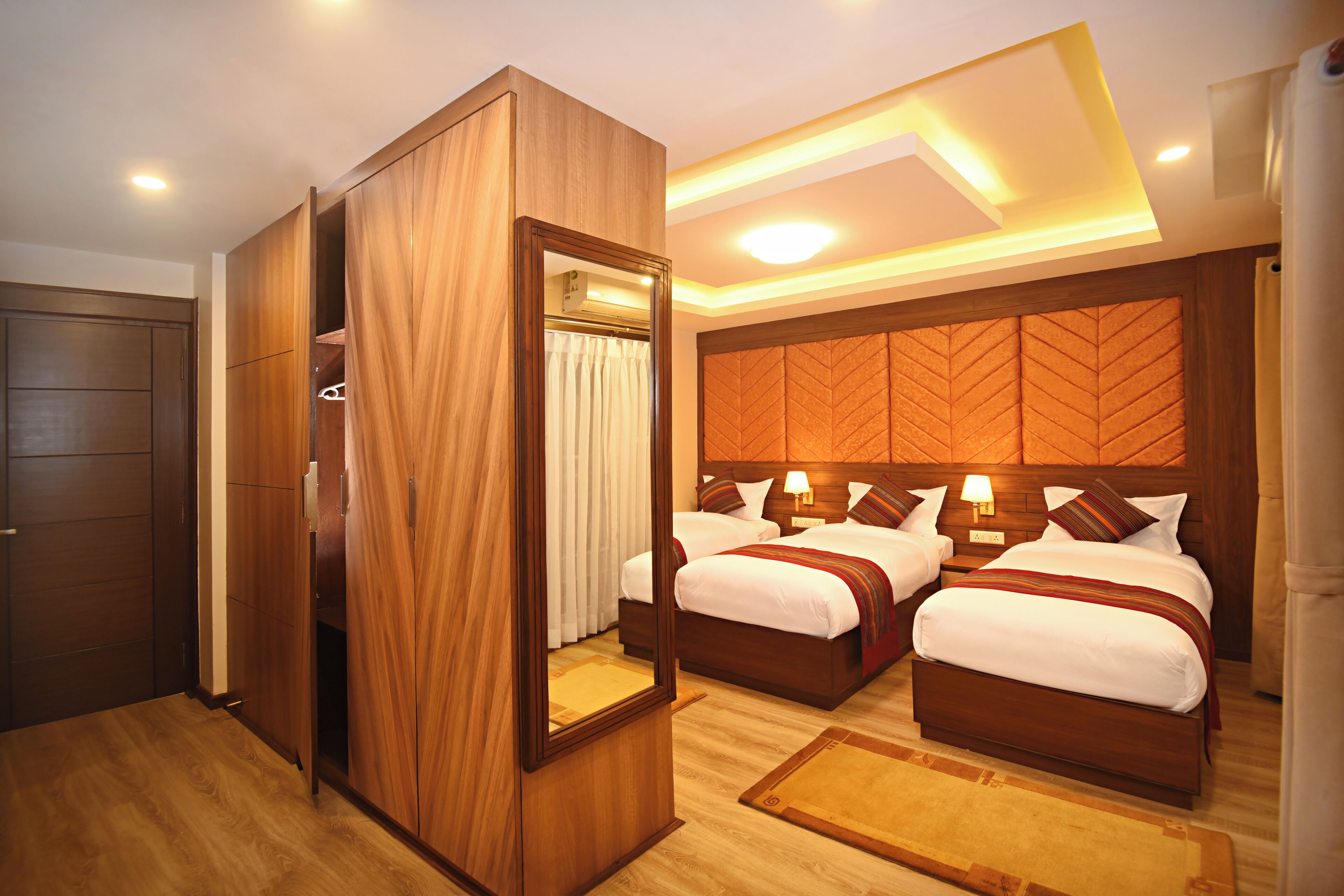 Habitación de hotel con dos camas, un armario de madera y un espejo grande.