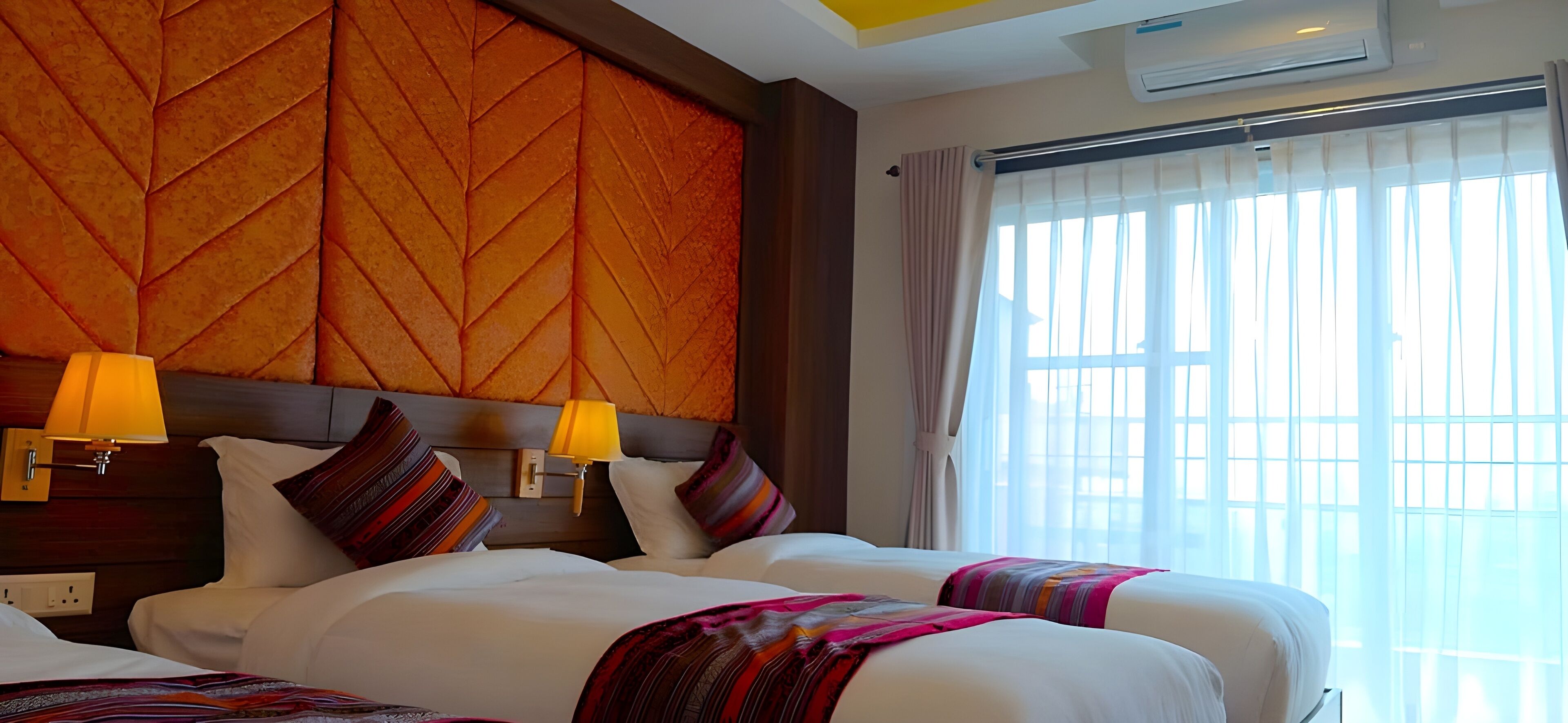 A hotel room with two beds, a wooden headboard, a window with curtains, and a wall-mounted air conditioner.