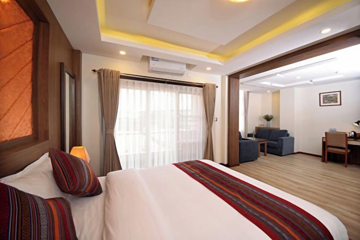 A hotel room with a large bed, a desk, and a sofa.