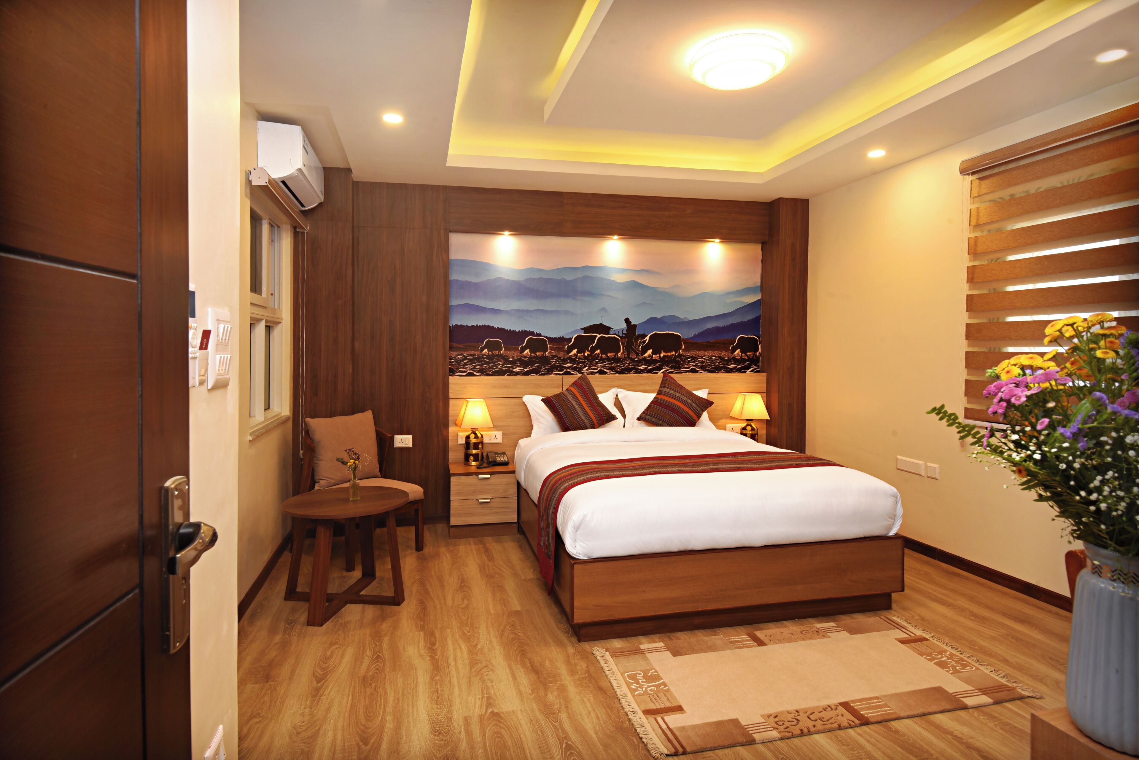 Un dormitorio con una cama de madera, una mesita de noche con una lámpara, una pequeña mesa y una ventana.