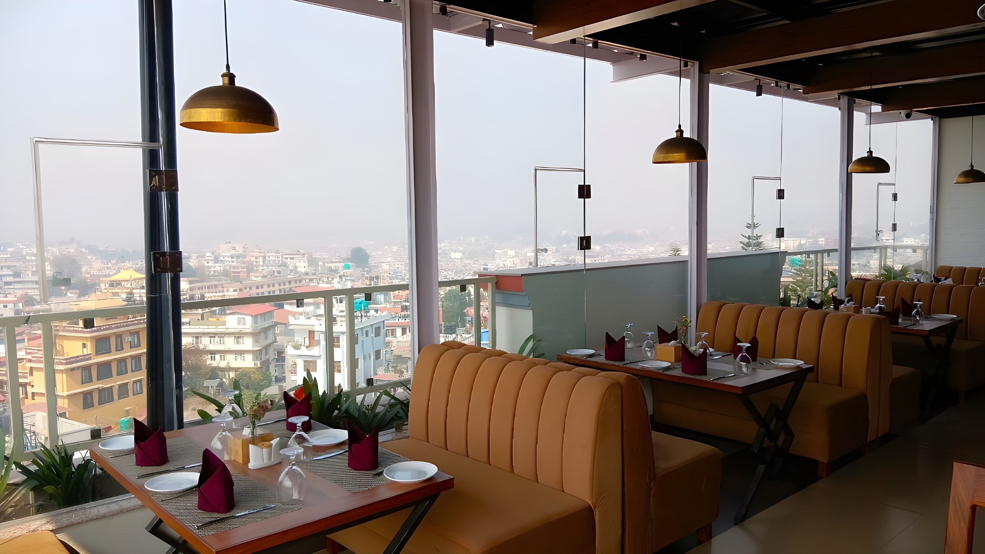 Un restaurante en la azotea con terraza, amplias ventanas y vistas a la ciudad.