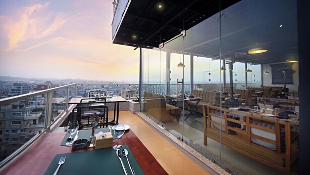 A high-rise restaurant with a panoramic city view, outdoor seating, and modern interior design. - Hotel Sherpani (Kathmandu)