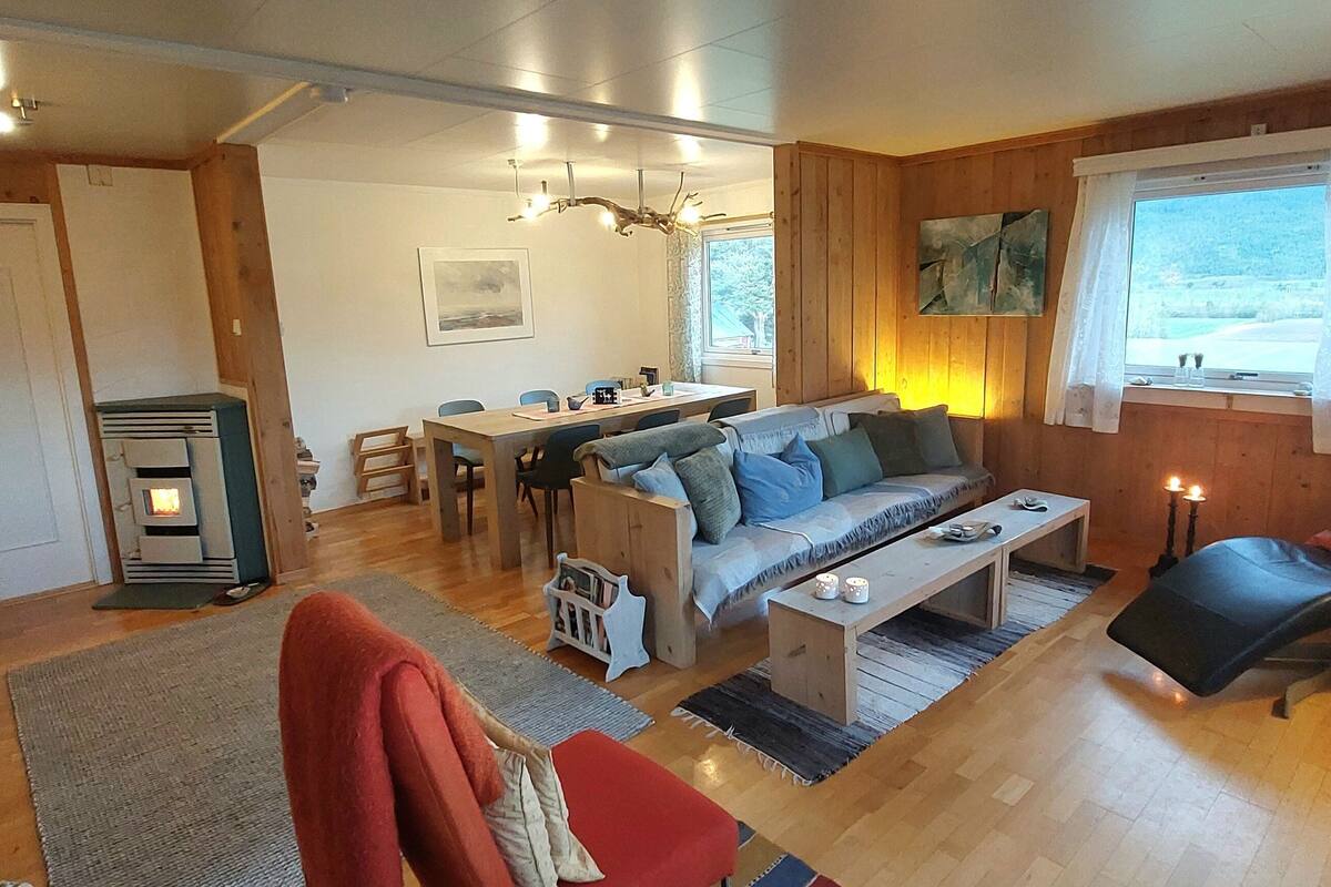 A cozy living room with a sofa, a coffee table, a dining area with chairs, and a fireplace.