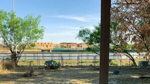 An outdoor area with a dirt ground, a metal fence, and a building in the background. - 3-bedroom house in beautiful Eagle Pass with WiFi (Eagle Pass)