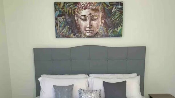 A neatly made bed with a grey headboard and white bedding. - 3-bedroom house in beautiful Eagle Pass with WiFi (Eagle Pass)