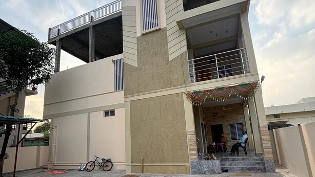 Un edificio residencial de varios pisos con un balcón, una escalera que conduce a la entrada y una bicicleta estacionada afuera.