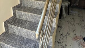 Una escalera con escalones de mármol y barandilla de metal.