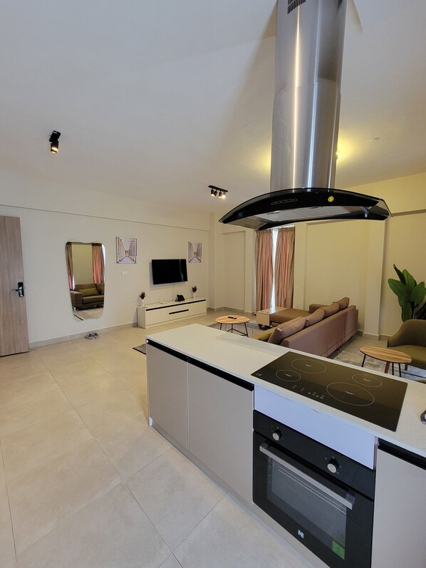 A modern kitchen with a built-in stove, oven, and a large stainless steel range hood. - Zarafa Suites (Nairobi)