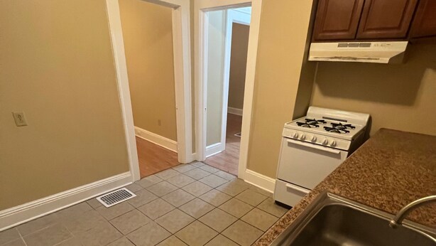 A kitchen with a granite countertop, stainless steel sink, and white stove. - Karan Luxury Apartment (Jersey City)