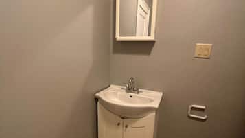 A bathroom with a white sink, mirror, and toilet.