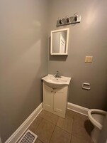 A bathroom with a white sink, mirror, and toilet.