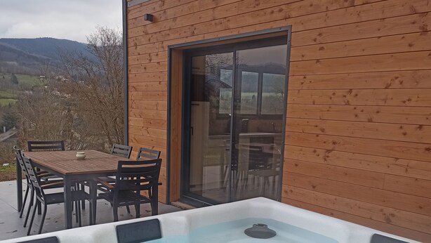 Une cabane en bois dotée d’un bain à remous et d’un coin repas avec des chaises et une table.