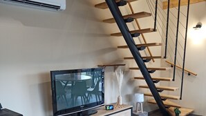 Un salon moderne avec un téléviseur, des meubles en bois, une cheminée et un escalier.