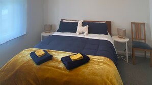 Een slaapkamer met een bed, een nachtkastje, een stoel en een raam.