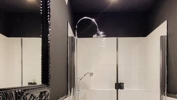 Ein modernes Badezimmer mit einer Duschkabine aus Glas, einem großen Spiegel und einem weißen Waschbecken.
