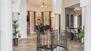 A spacious interior with high ceilings and arched columns, a central dining area with a round table and chairs, and a kitchen area with dark cabinetry. - Villa, Private Pool, 5-Minute Walk to the Beach (La Herradura)