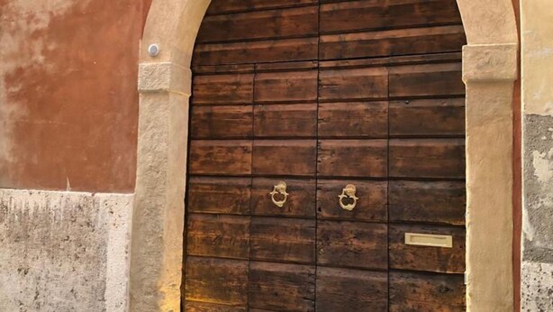 Una puerta de madera con dos tiradores de latón, enmarcada en un arco de piedra.