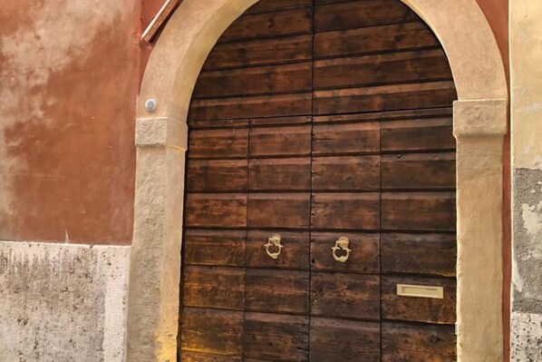 Una puerta de madera con dos tiradores de latón, enmarcada en un arco de piedra.