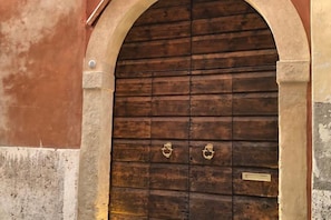 A wooden door with two brass handles, set within an arched stone frame.