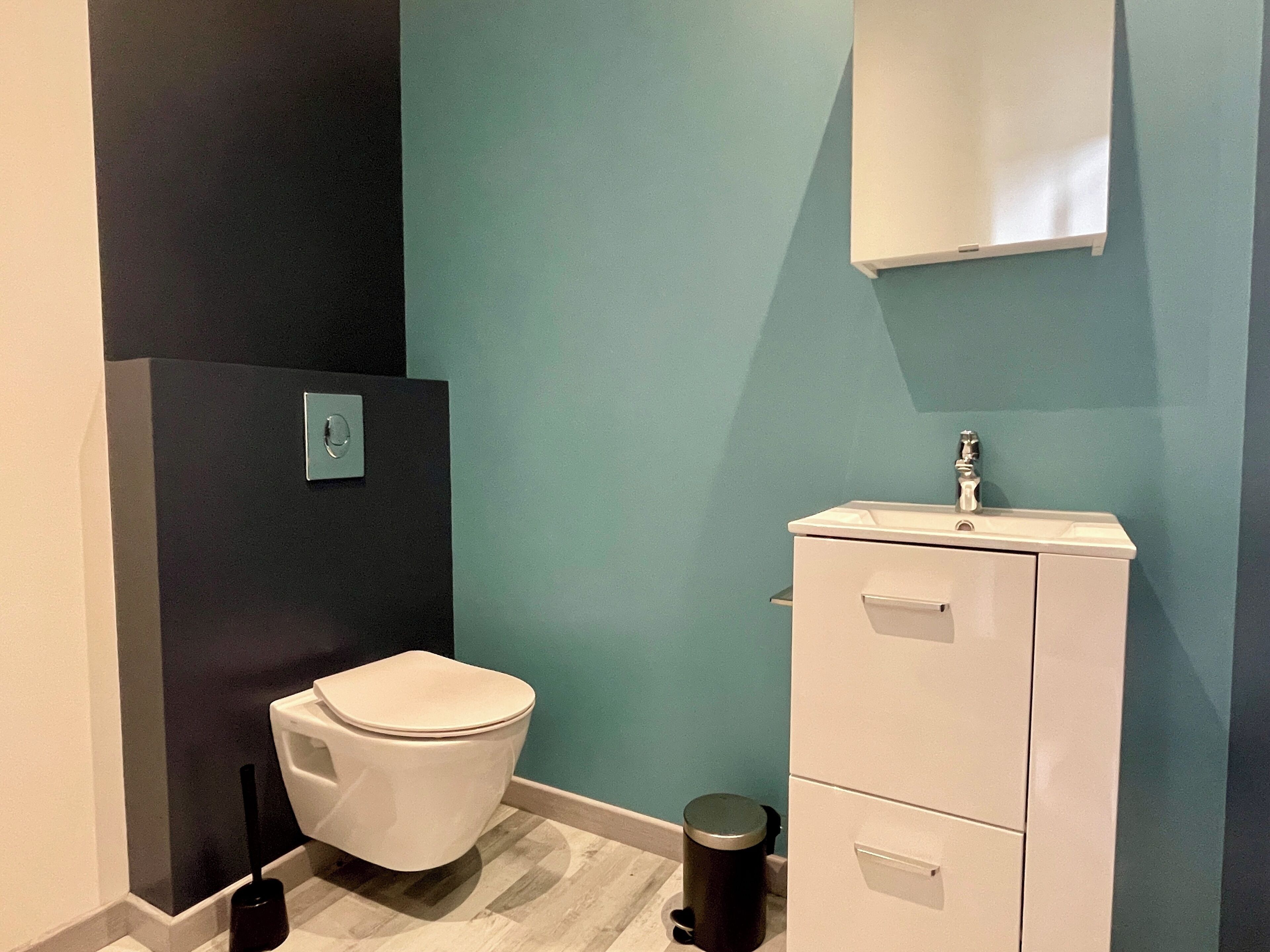 Un baño con inodoro, lavamanos y cubo de basura.
