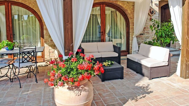 An outdoor patio with a table, chairs, and sofas under a wooden pergola.