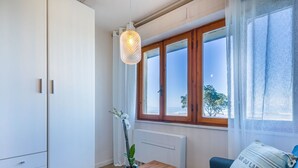 A modern room with a wooden bench, a blue sofa, and a view of the sea through large windows.