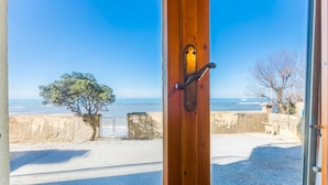 A view from a room with a wooden door leading to a beach.
