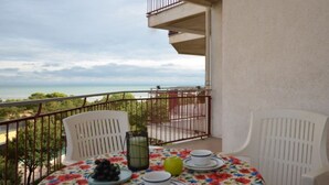 A balcony with a table set for two, a view of the sea, and a railing. - Holiday flat with seaview terrace (Lignano Sabbiadoro)