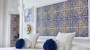 Habitación de hotel con cama, almohadones decorativos y pared de baldosas estampadas.