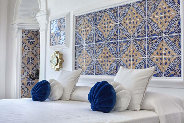 A hotel room with a bed, decorative pillows, and a patterned tile wall. - Estate4home - Regina Dar (Positano)