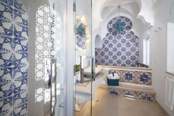 Un bagno con cabina doccia in vetro, lavandino e parete rivestita con piastrelle decorative.