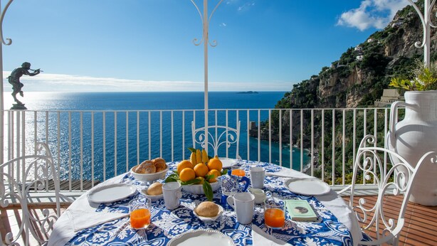 Una mesa preparada para el desayuno con vista al mar y un acantilado.