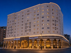 A large hotel with multiple floors, a curved facade, and a prominent entrance with arches.