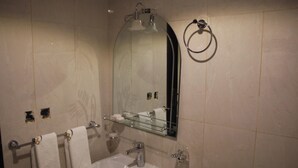 A bathroom with a white sink, a glass shelf, a towel rack, and a mirror. - Burj Mawaddah Hotel (Madinah)