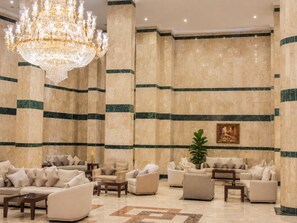 A luxurious lobby with a grand chandelier, plush seating, and marble walls.