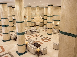 A spacious lobby with high marble columns, a grand chandelier, and comfortable seating areas.