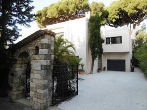 Una casa moderna con ingresso in pietra, cancello in metallo e vialetto lastricato che conduce a un garage.