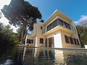 A modern two-story house with a swimming pool in front.