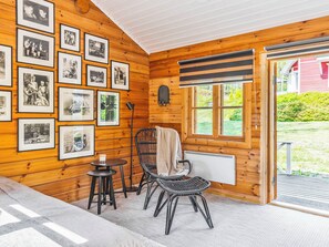 A cozy room with wooden walls, a black wicker chair, a small table, and a radiator.