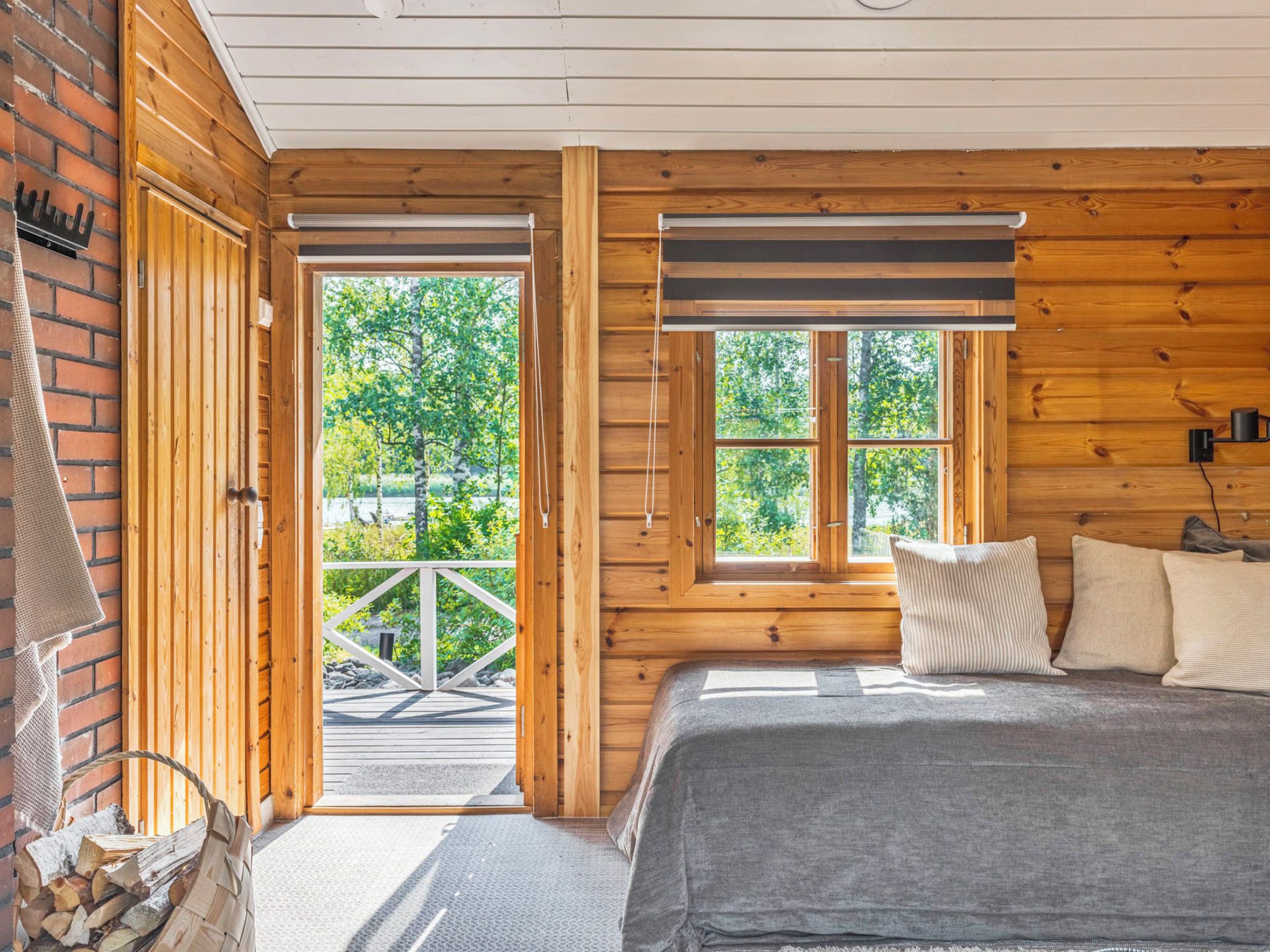 A wooden cabin room with a bed, a fireplace, and a view of trees.
