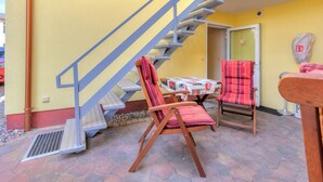 Una escalera que lleva a una puerta, una silla con un cojín a rayas y una mesa con mantel de flores.
