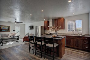 Une cuisine moderne avec des meubles en bois, un îlot central et un coin repas avec des chaises.