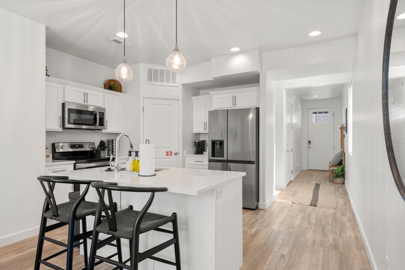 A modern kitchen with white cabinetry, stainless steel appliances, and pendant lighting.