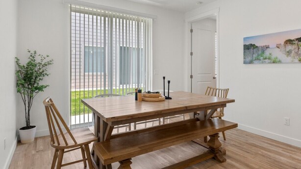 Un comedor con una mesa y sillas de madera, una planta en maceta y un cuadro en la pared.